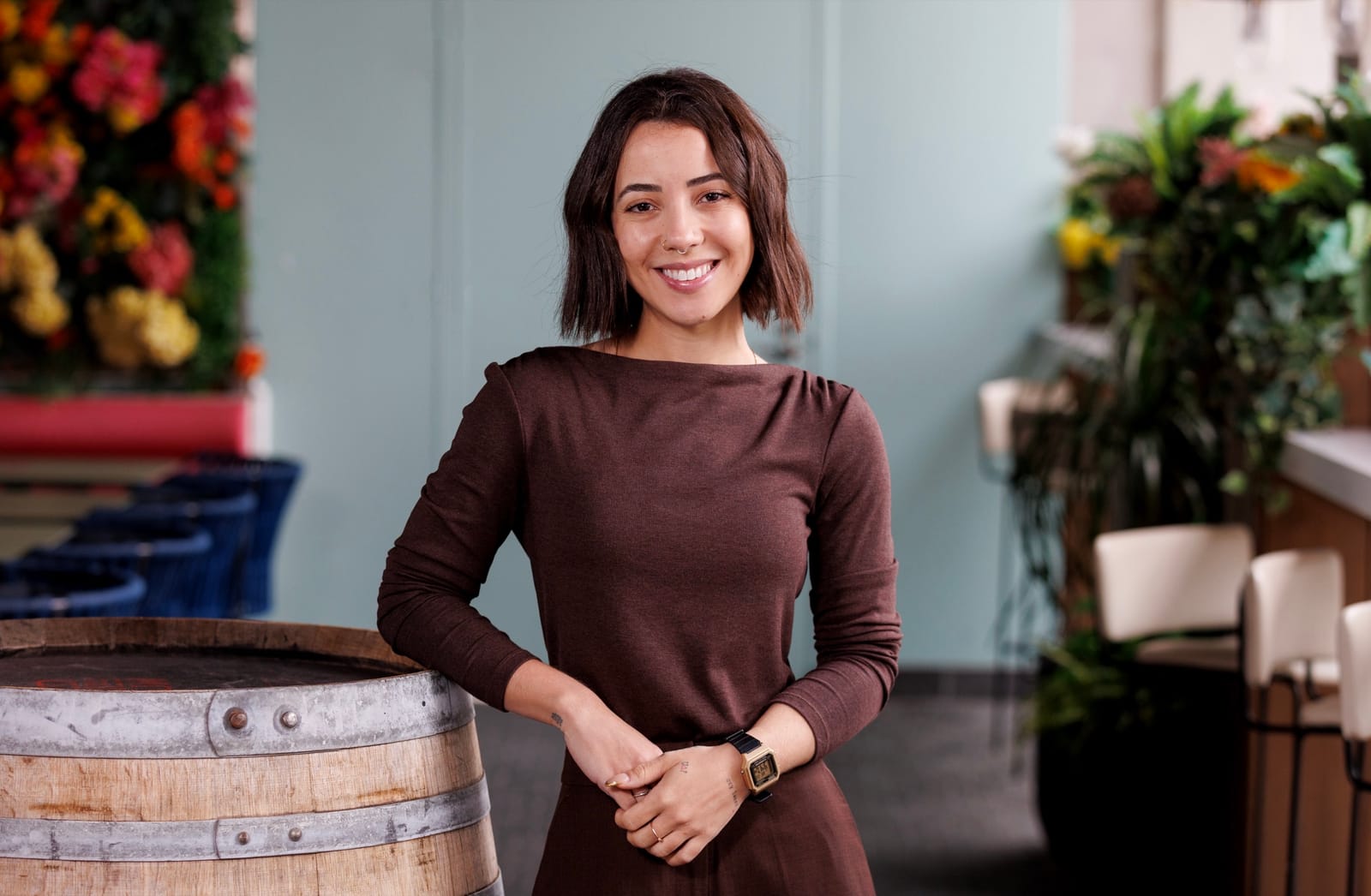 A TFE Hotels team member smiling to camera beside a wine barrel