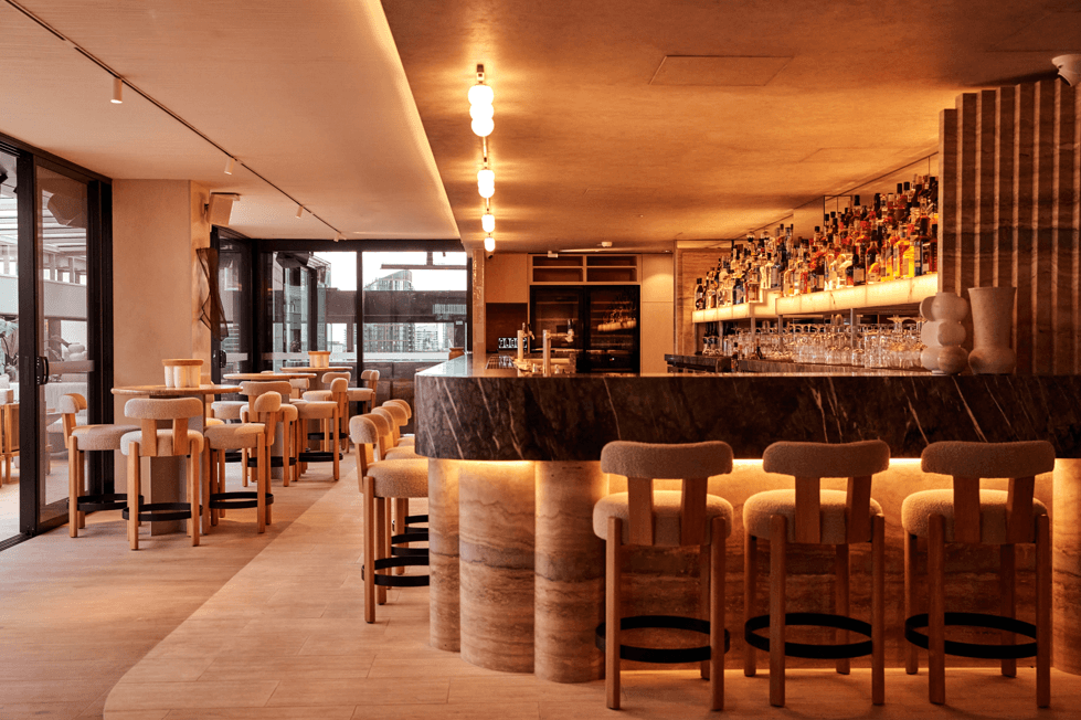 A hotel bar and lounge with a curved marble counter and stools