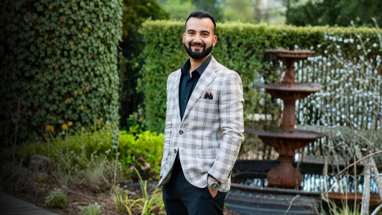 A TFE Hotels leader in a checked blazer standing in a hotel garden courtyard