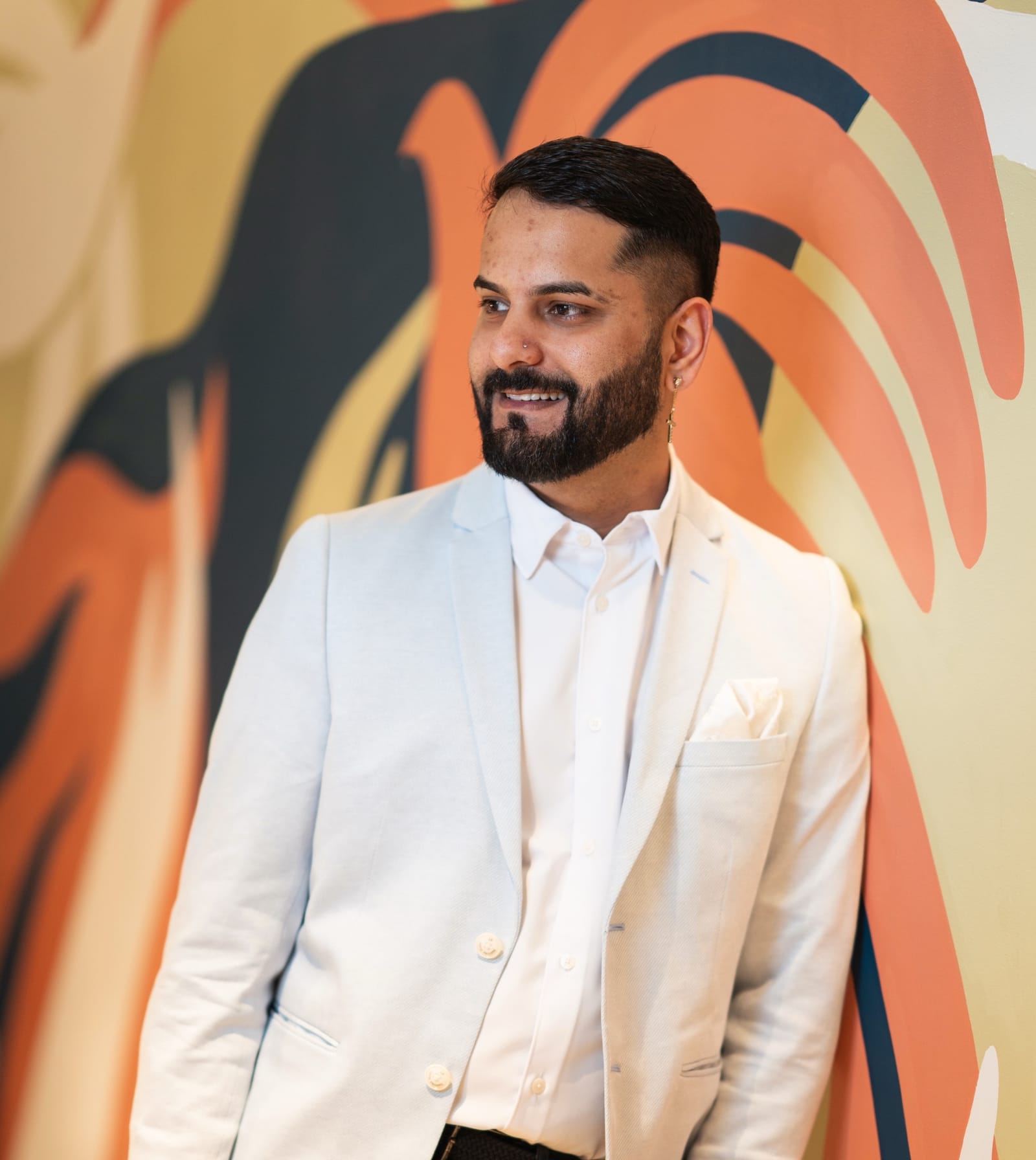 A TFE Hotels team member in a white jacket in front of a brightly coloured mural